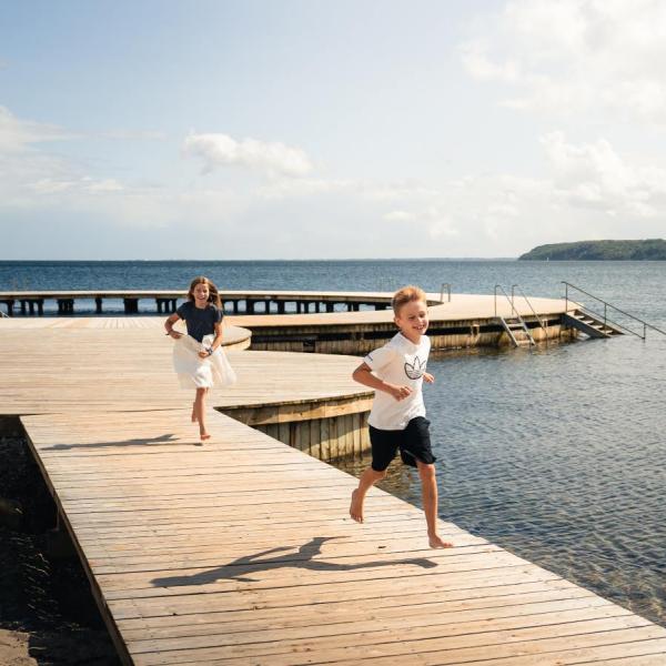 Pige og dreng løber på cirkelbroen på Østerstrand i sommervejr