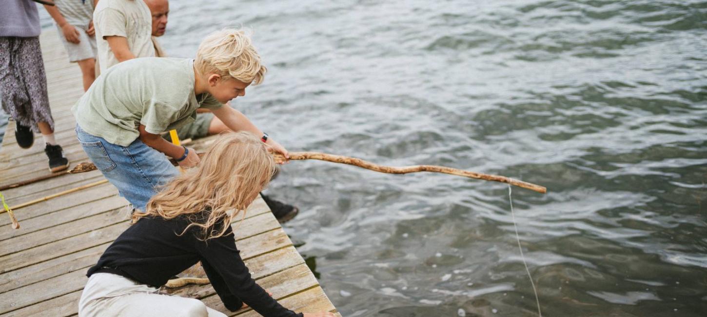 Børn fisker efter krabber ved stranden