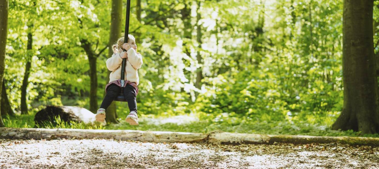 Pige på gynge på naturlegeplads