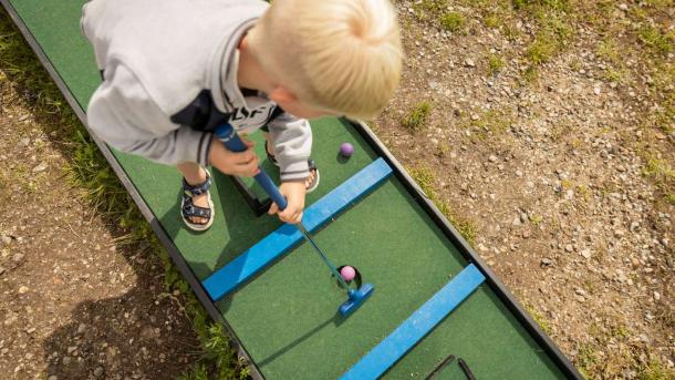 Dreng spiller minigolf i Havnens Oase