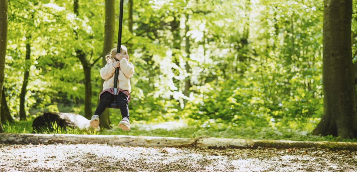 Pige på gynge på naturlegeplads