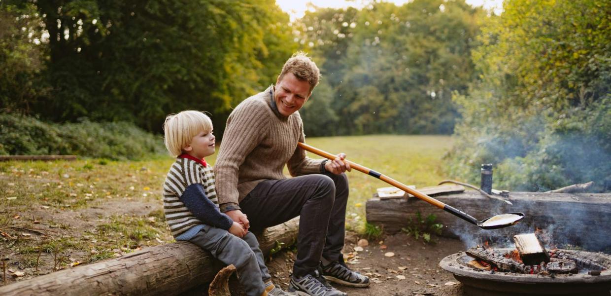Far og søn sidder ved bålet på shelterplads