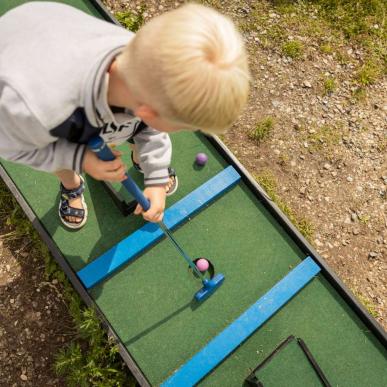 Dreng spiller minigolf i Havnens Oase